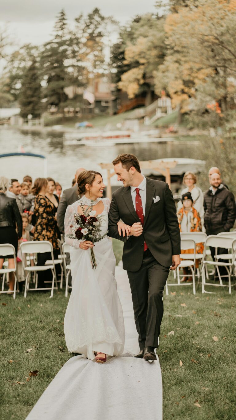 Couple walking after wedding ceremony outdoors, woman in a white dress with sleeves — ideal for a spring or fall wedding guest dress.